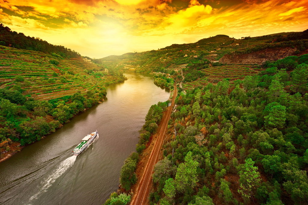 Rivier de Douro in de Dourovallei met wijngaardterrassen en een boot bij zonsondergang.