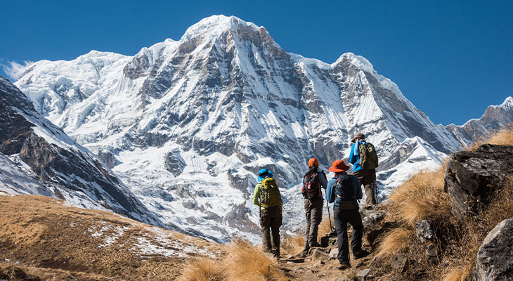Annapurna Wandelaars met rugzakken op bergpad met uitzicht op besneeuwde bergtoppen.
