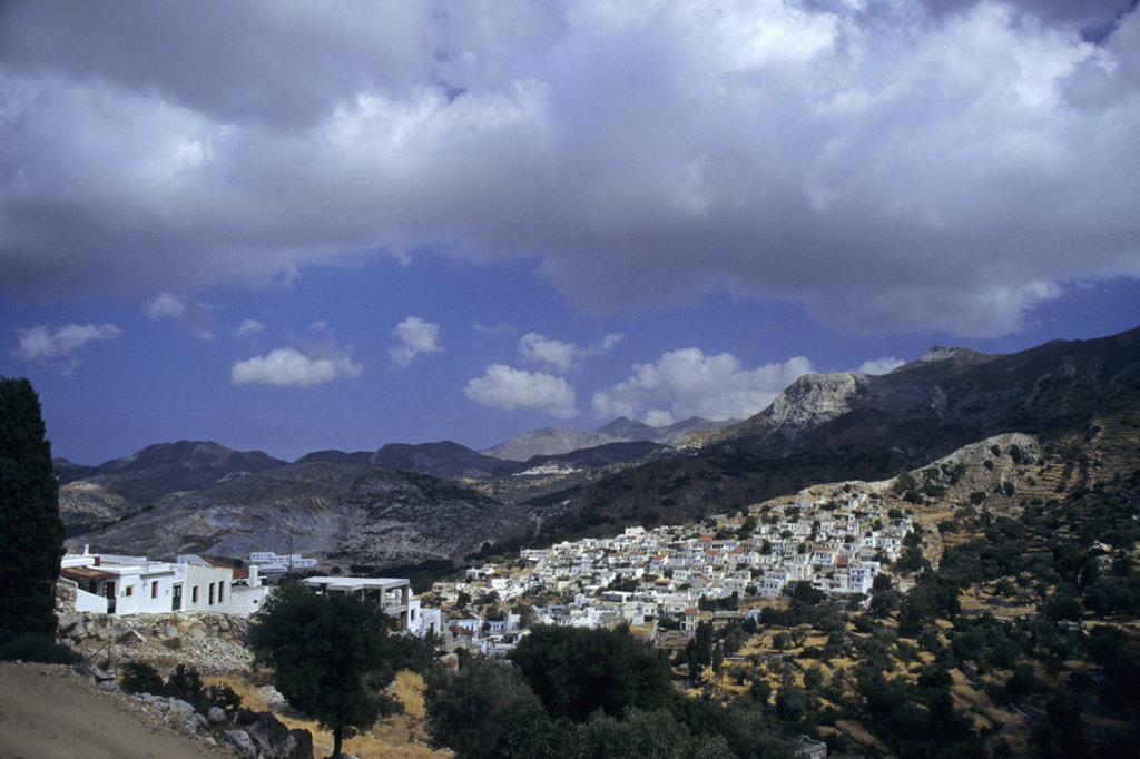 Wit dorp in berglandschap op Naxos, Griekenland, onder een dreigende wolkenlucht.