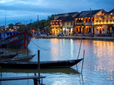 Avondzicht op de rivier in Hoi An met verlichte huizen en boten op het water.