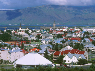 Uitzicht over Reykjavik met kleurrijke daken, kerkspitsen en bergen op de achtergrond.