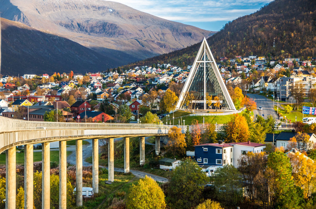 Arctische kathedraal in Tromsø met brug, kleurrijke huizen en bergen tijdens een groepsrondreis Noorwegen.