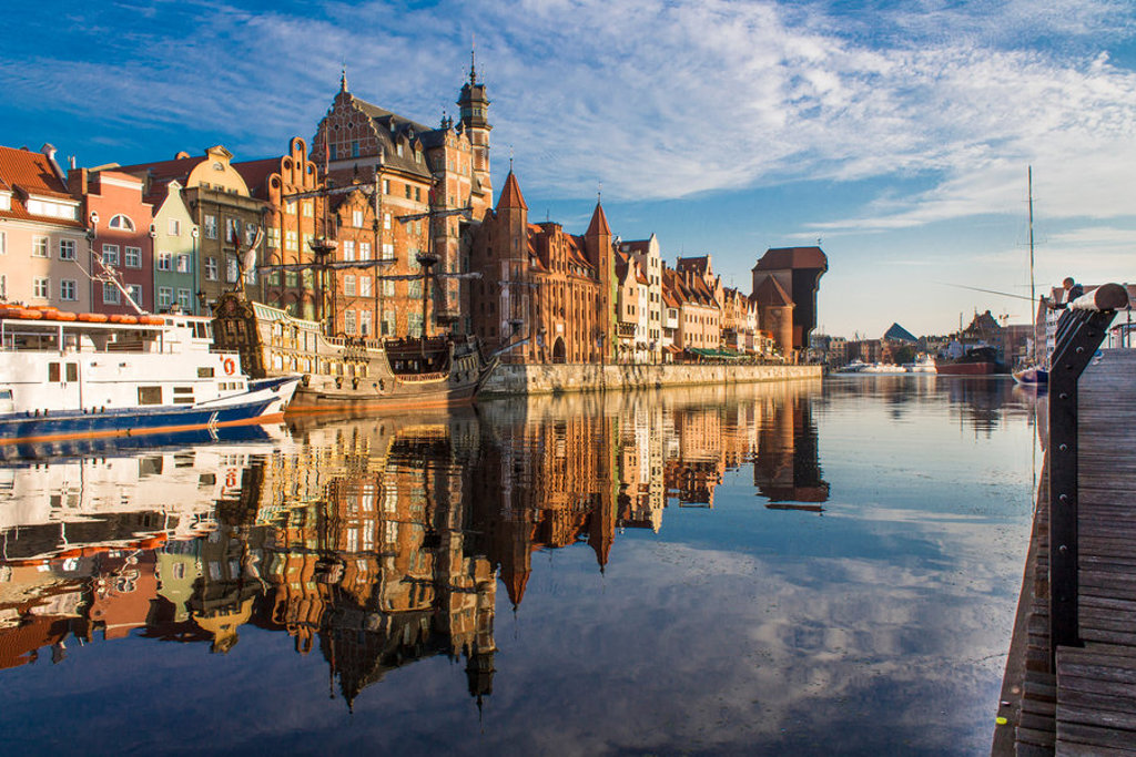 Historische gevels aan de Motława-rivier in Gdańsk, Polen, met schepen en weerspiegeling in het water.