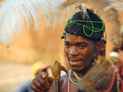 Man met kralen en veren hoofdtooi tijdens een voodoo-ceremonie in Benin, reisroute Ghana, Togo en Benin.