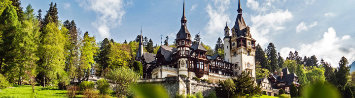 Peleș-kasteel in Sinaia, Roemenië, omringd door bos en bergen.