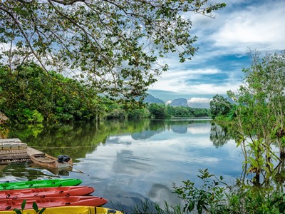 Kajaks aan de oever van een rustige rivier met groene jungle en kalksteenbergen op de Route Thailand.