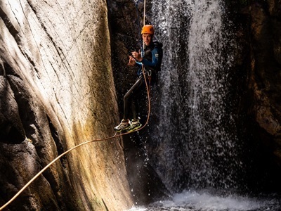 Canyoning in Route Canigou: deelnemer daalt met touw langs een waterval in een smalle kloof.