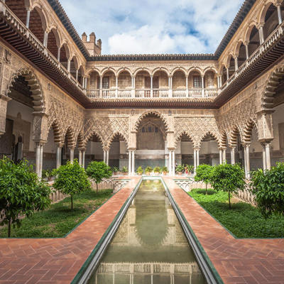 Binnenplaats met Moorse bogen en waterpartij in het Real Alcázar van Sevilla tijdens groepsrondreis Andalusië.
