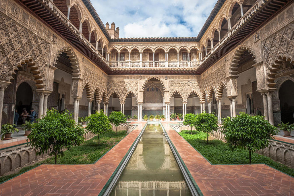 Binnenplaats met Moorse bogen en waterpartij in het Real Alcázar van Sevilla tijdens groepsrondreis Andalusië.