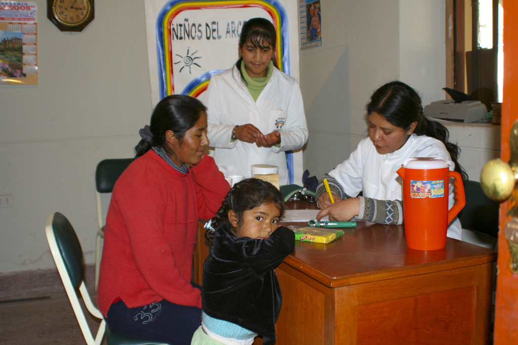 Medische check-up in Peru: vrouw met kind bij zorgverleners in een kliniek.