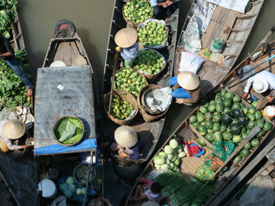 Drijvende markt in de Mekongdelta met boten vol mango’s, watermeloenen en groenten.
