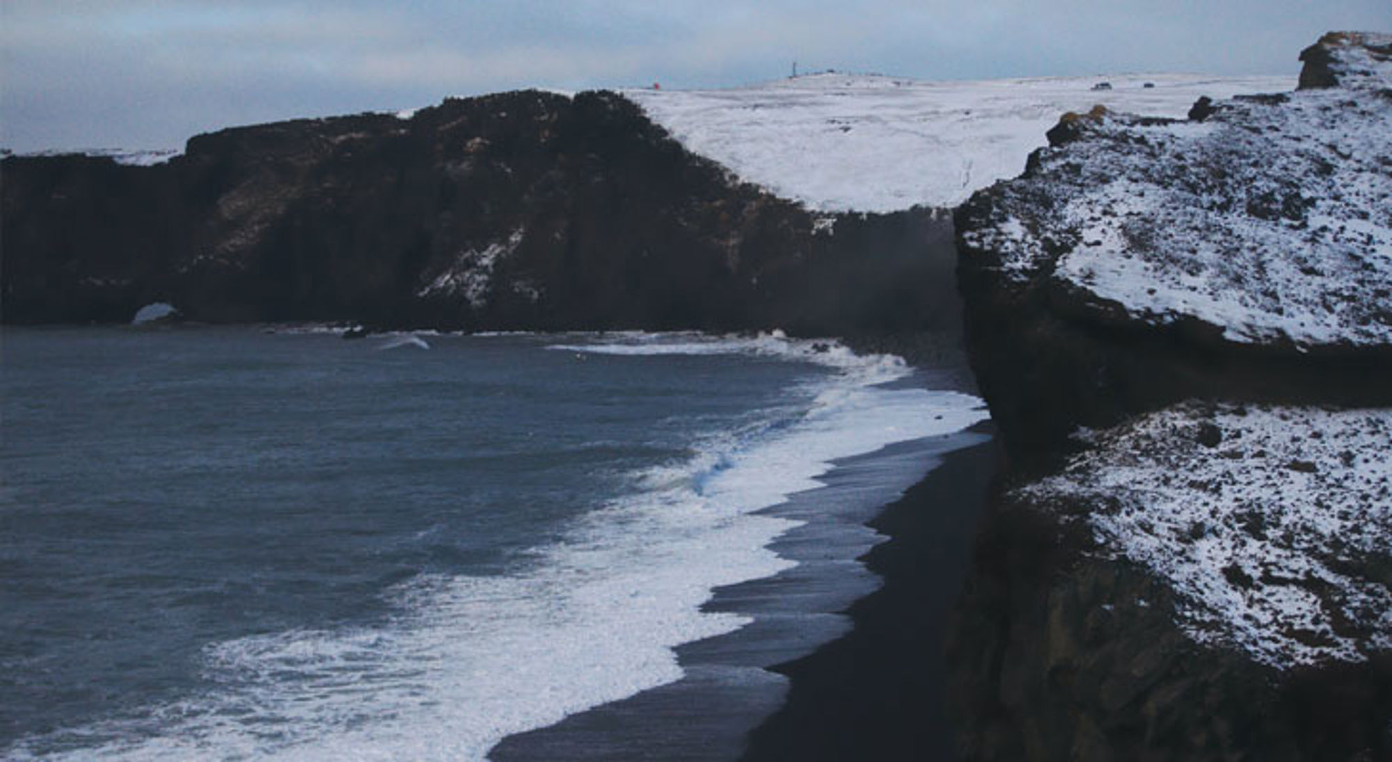 Vik zwart strand IJsland Zwarte zandkust met besneeuwde kliffen en golven aan de zuidkust van IJsland.