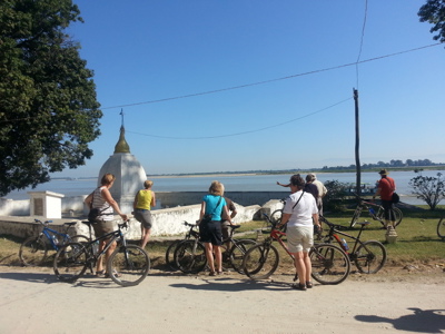 Fietsers pauzeren bij een pagode aan de rivier tijdens de Route Birma/Myanmar reis van 25 dagen, dag 13.