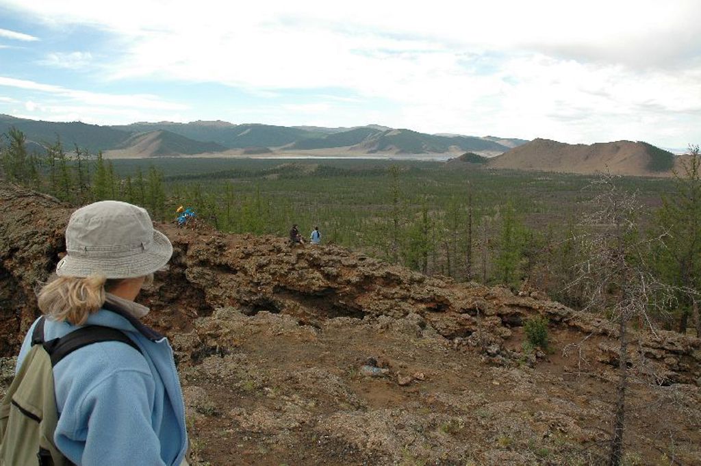 Wandelaar met rugzak kijkt uit over de heuvels en uitgestrekte steppe tijdens groepsrondreis Mongolië.