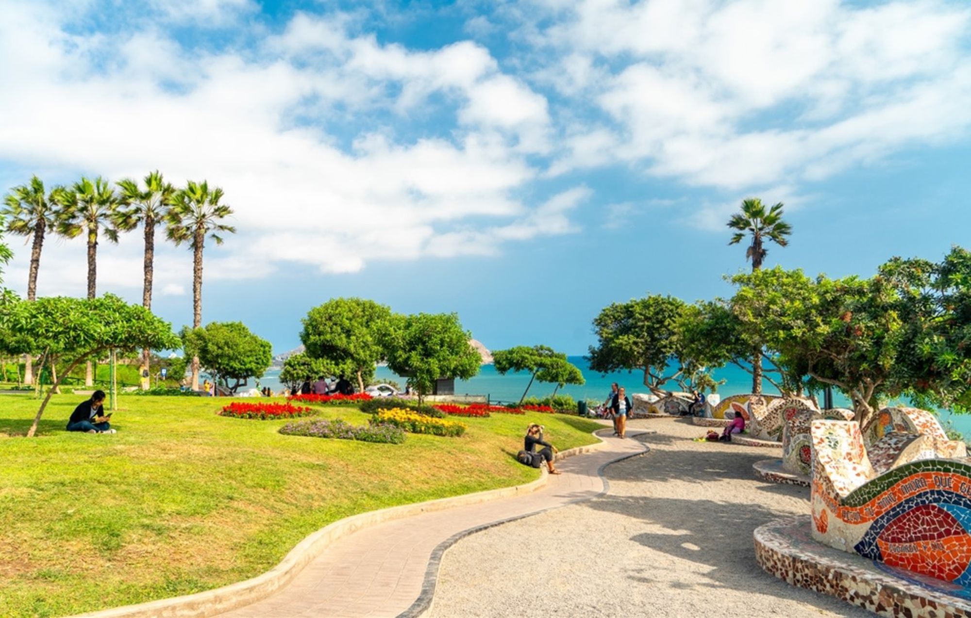 Park aan de kust in Lima, Peru, met palmbomen, mozaïekbanken en uitzicht op de Stille Oceaan.
