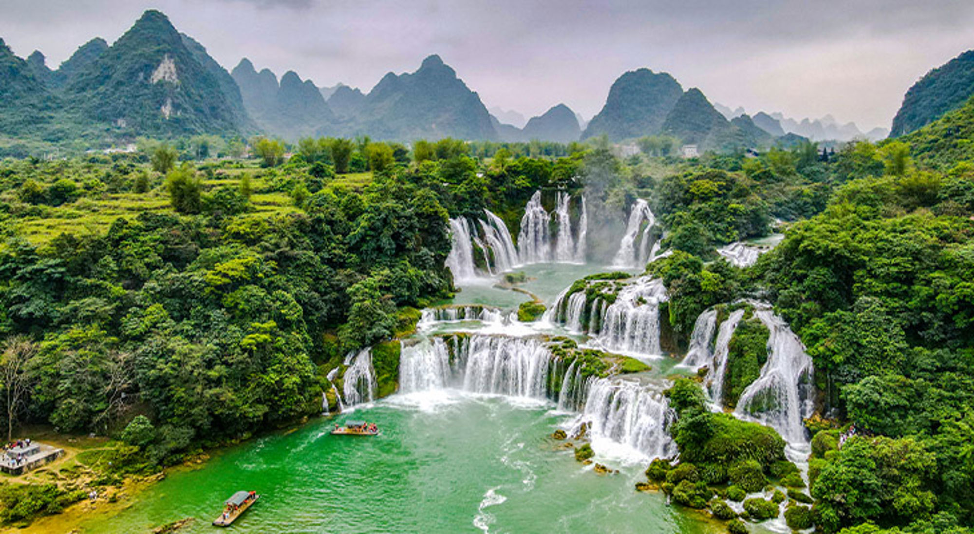 Watervallen Vietnam Panoramisch uitzicht op een waterval met turquoise rivier, omringd door groen en karstbergen.