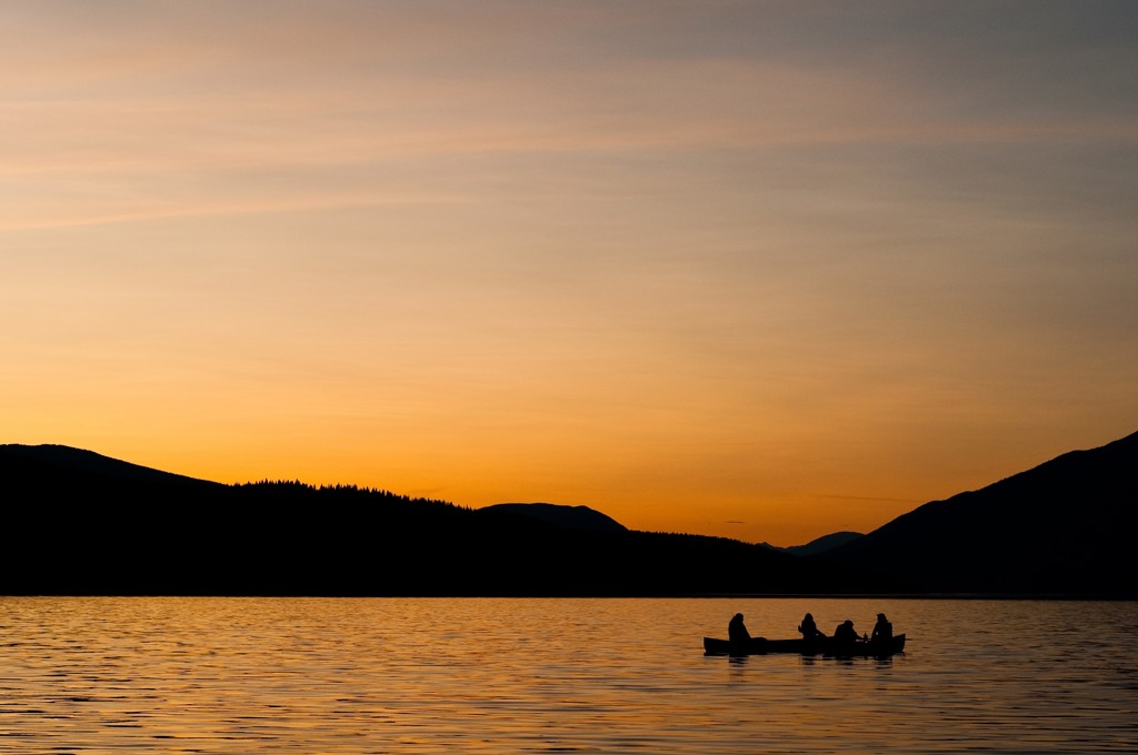 Silhouet van kanoërs op een meer bij zonsondergang in Canada West.