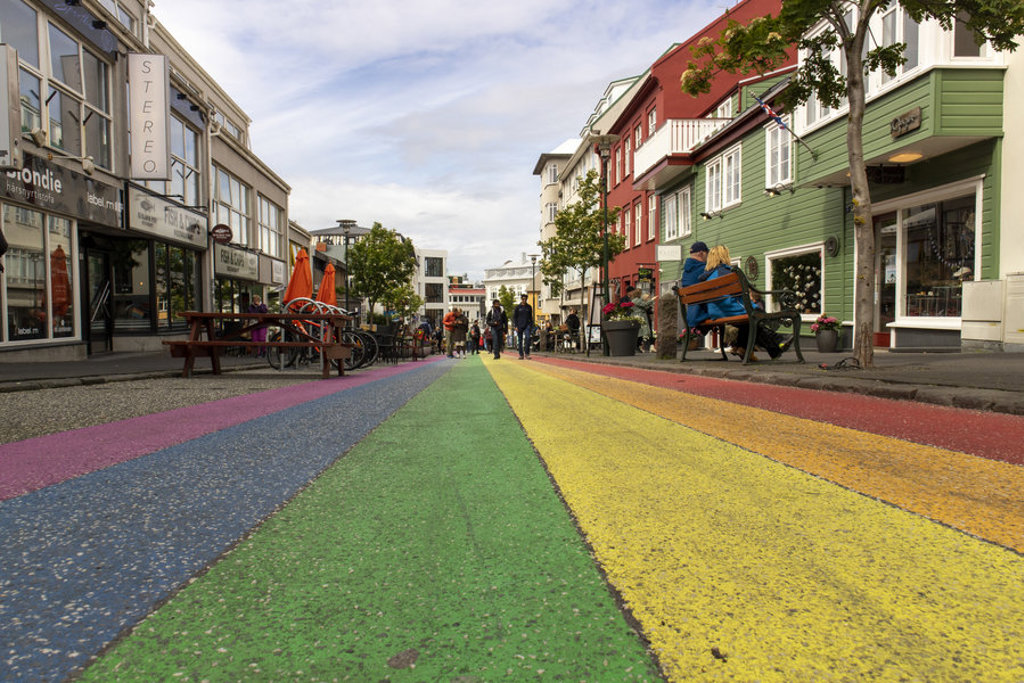 Regenbooggekleurde straat in Reykjavik met kleurrijke huizen en terrassen, tijdens de groepsrondreis Vier Arctische eilanden.