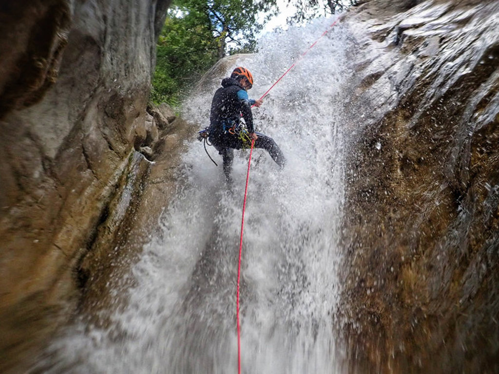 Canyoning in de Pyreneeën bij Canigou, Frankrijk: afdalen langs een waterval met touw en helm.