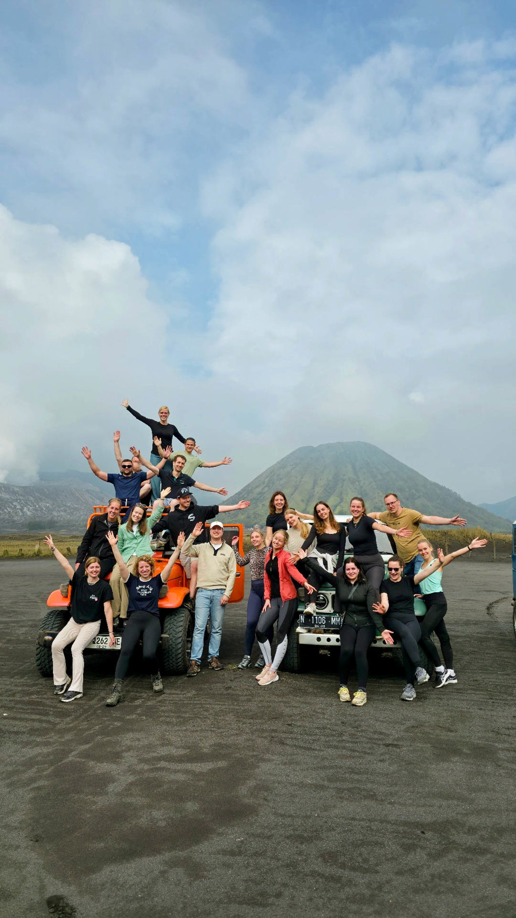 Groep 22-35ers poseert bij jeeps met vulkaanlandschap op Java, Indonesië.