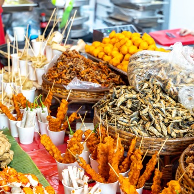 Streetfoodkraam in Manilla met gefrituurde snacks en vis op stokjes in manden en bekers.
