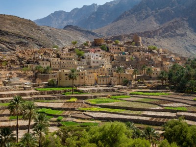 Traditioneel dorp in het Hajar-gebergte bij terrassen met palmbomen, route Oman en Dubai.