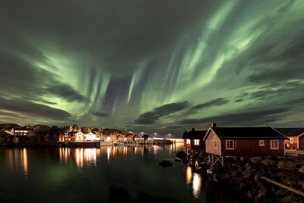 Noorderlicht boven vissershuisjes aan de kust van de Lofoten in Noorwegen.