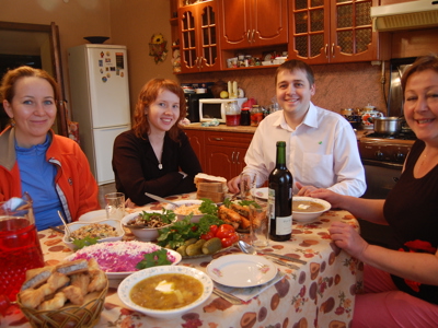 Gezin geniet van een huisgemaakte maaltijd aan tafel in een Russische keuken tijdens een 14-daagse rondreis door Rusland.