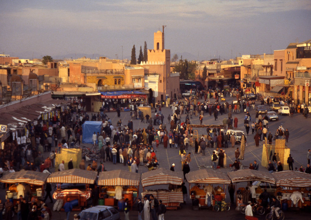 Drukke markt op het Djemaa el Fna-plein in Marrakech, Marokko, met kraampjes en minaret.