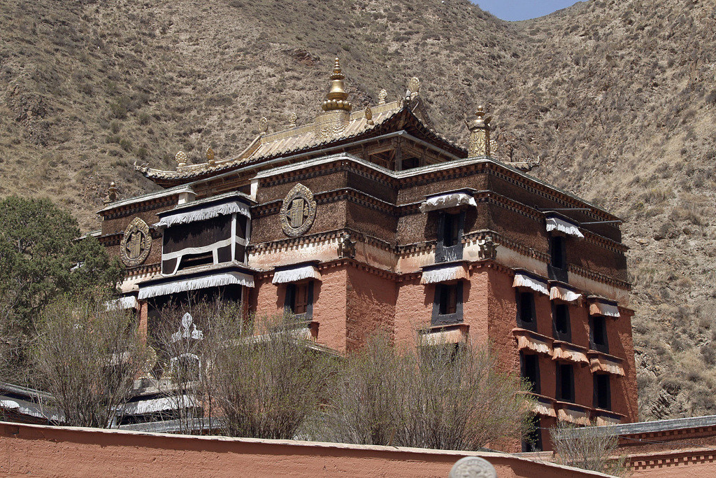 Tibetaans boeddhistisch klooster met goudkleurig dak tegen een berghelling, tijdens groepsrondreis Tibet en Nepal.