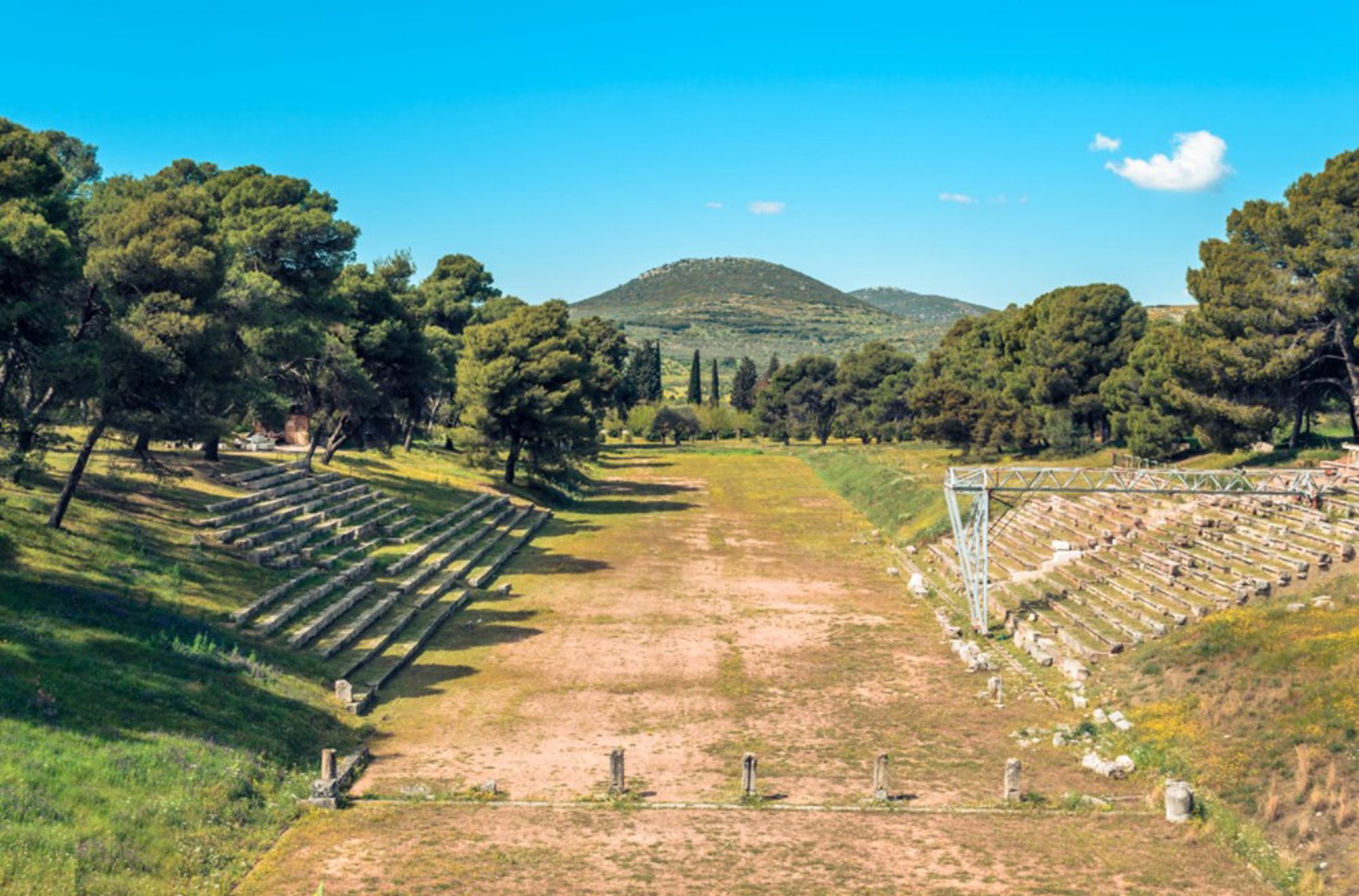 Oud stadion van Nemea in Griekenland met stenen tribunes en hardloopbaan tussen pijnbomen.