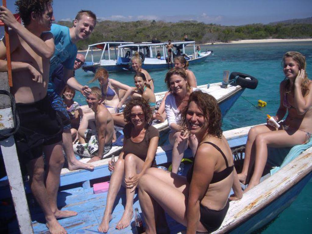 Gezin op een boot bij een strand met azuurblauw water tijdens familiereis Java & Bali in Indonesië.