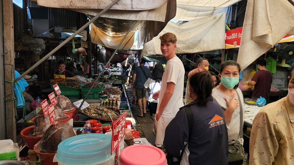 Traditionele longtailboot in Thailand met drijvende marktkramen langs het water.