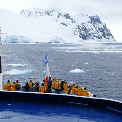 Expeditieschip met passagiers bij ijsbergen en besneeuwde bergen tijdens groepsrondreis Antarctica.