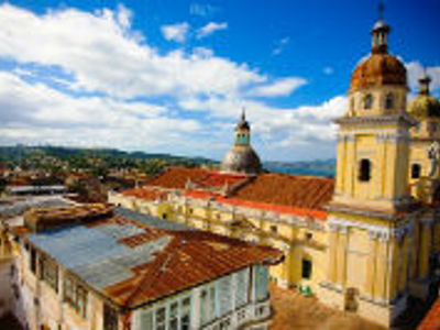 Uitzicht over Trinidad, Cuba met kleurrijke daken en de toren van een kerk onder een blauwe lucht.