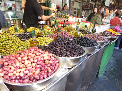 Marktkraam met schalen vol olijven, gedroogd fruit en flessen olijfolie tijdens de rondreis Jordanië en Israël.