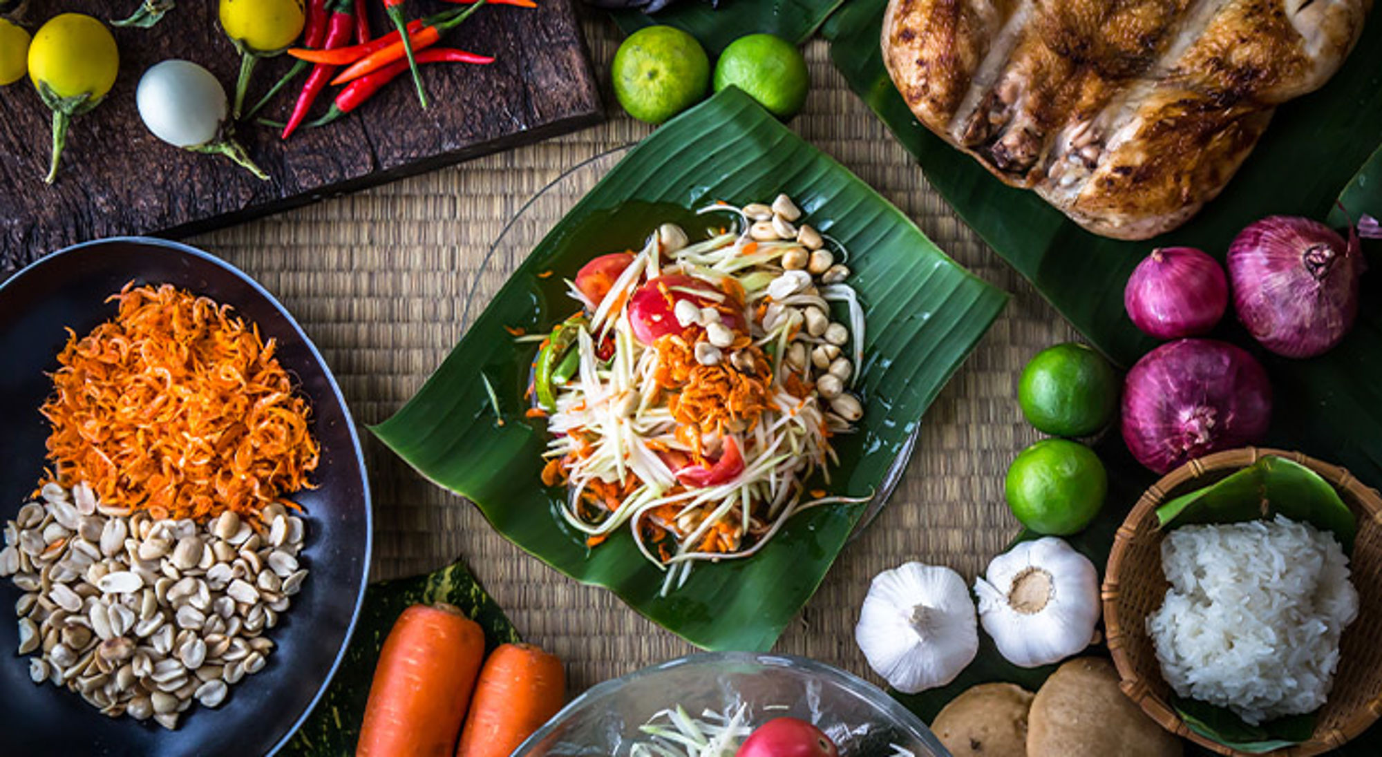 Thaise papajasalade op bananenblad met pinda’s, limoen, chilipepers en andere verse ingrediënten.