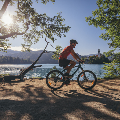 Fietser langs het Meer van Bled in Slovenië, met uitzicht op de kerk op het eiland.