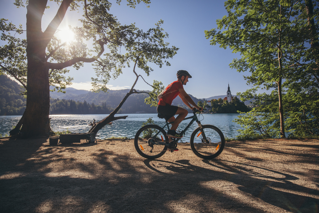 Fietser langs het Meer van Bled in Slovenië, met uitzicht op de kerk op het eiland.