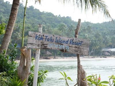 Houten bord met “Koh Talu Island Resort” aan het strand op Koh Talu, Thailand.
