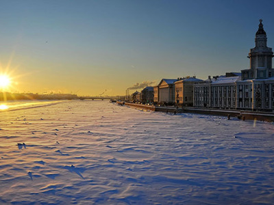 Zonsondergang boven de bevroren Neva met de universiteitskade in Sint-Petersburg, Rusland.