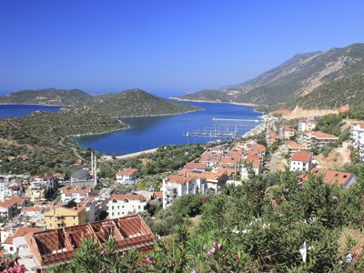 Uitzicht op de haven en baai aan de Turquoise Kust in Turkije, met rode daken en bergen op de achtergrond.