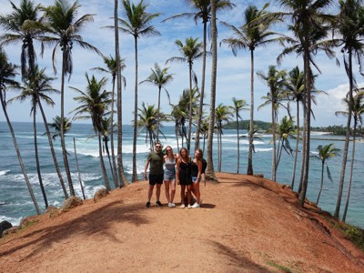 Reizigers bij palmbomen op een klif met uitzicht op zee aan de kust van Sri Lanka.