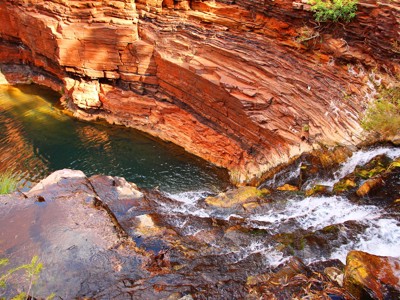 Waterval stroomt in een rotsachtige kloof met roodgelaagde wanden in West-Australië.