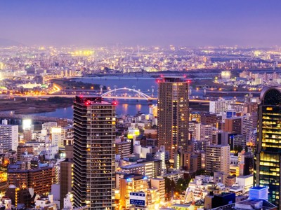 Avondzicht op de skyline van Osaka met verlichte wolkenkrabbers en bruggen over de rivier.