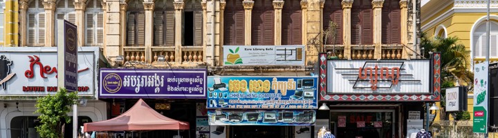 Straatbeeld in Battambang met historische gevels, winkels en scooters in het centrum.