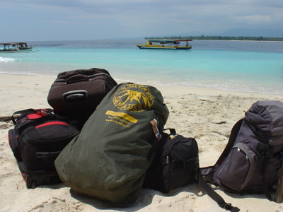 Reistassen op het strand van Gili Air met turquoise zee en boot op de achtergrond.