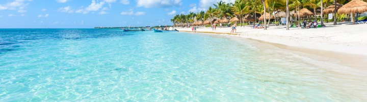 Wit zandstrand met palmbomen en helderblauw zeewater aan de Riviera Maya in Mexico.