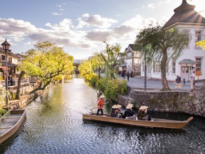 Boottocht over het kanaal in Kurashiki met historische pakhuizen en wilgenbomen in de namiddagzon.