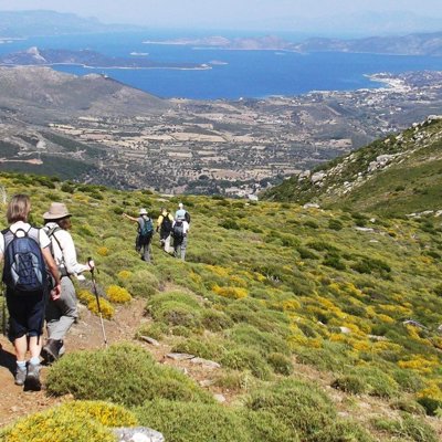 Wandelaars op bergpad op Evia, Griekenland, met uitzicht op de kust en dorpen tijdens een wandelvakantie.